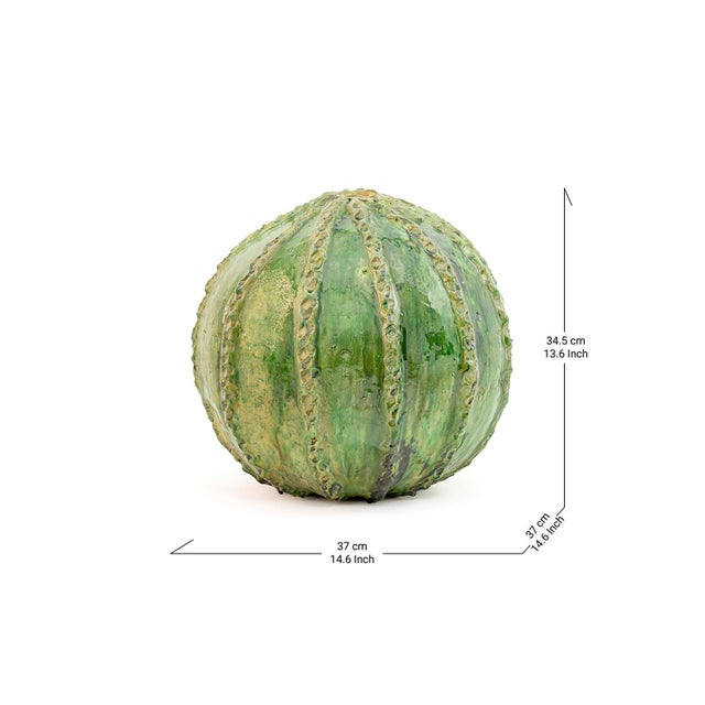 Cloaked in a verdant glaze with ridged detailing, this spherical Tamegroute pottery piece mirrors the lushness of a desert...