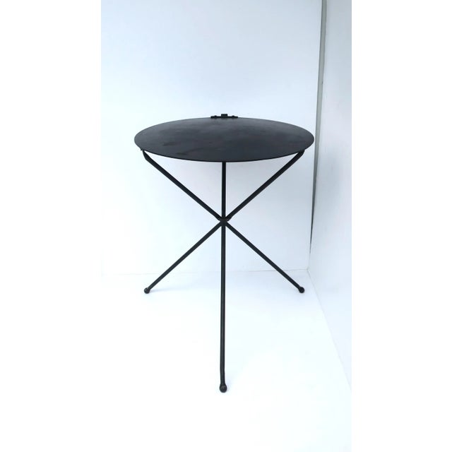 A substantial black metal end or side table with circular top and tripod base, circa late-20th century. Table is a...