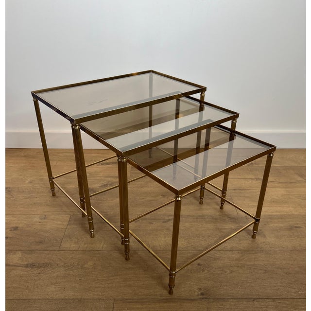This beautiful set of neoclassical-style nesting tables is made of brass with smoked glass tops. It is a French work by...