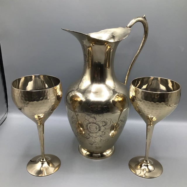 Floral etched handmade 36 ounce brass water/wine pitcher with 2 brass hand pounded wine goblets. Both goblets as well as...