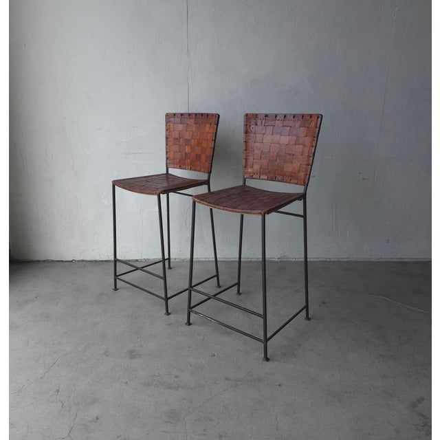 Pair of perfectly patinaed, woven leather, bar stools. Stools have beautifully worn leather woven on solid black iron...