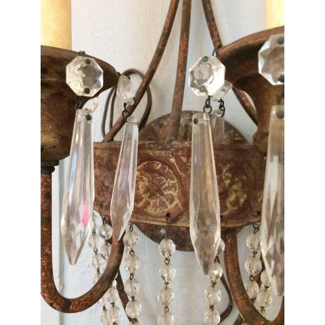Two iron and tole wall sconces having two arms and a bronze gilt patina as well as lovely cascades of crystals with a...