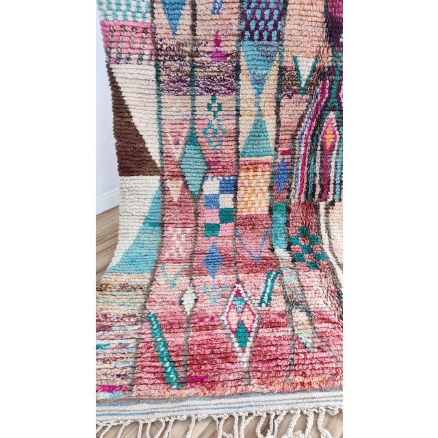 One-of-a-kind handwoven Moroccan rug. A patchwork Boujaad in dusty rose and clay — angular teepee-line figures and...