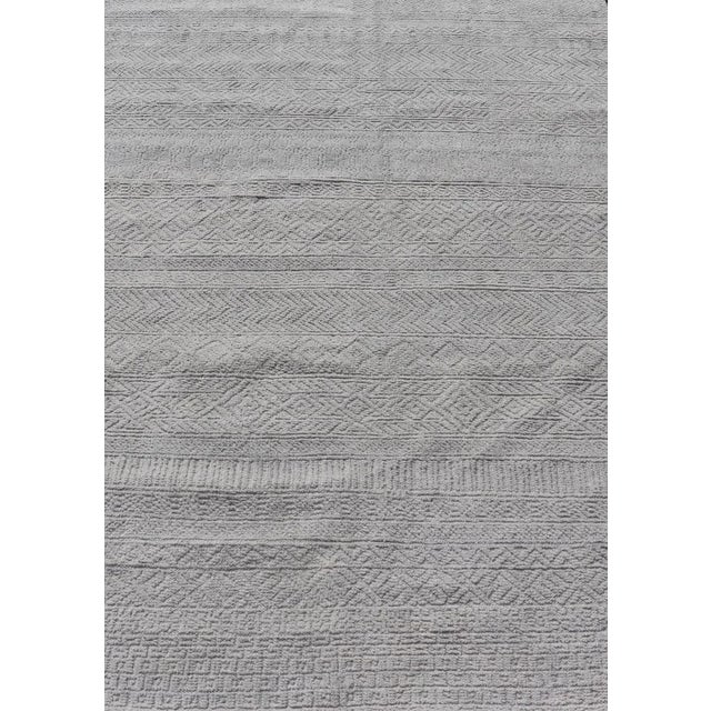 This modern tribal Oushak rug has been hand-knotted in wool. The rug features a modern, all-over sub-geometric design,...