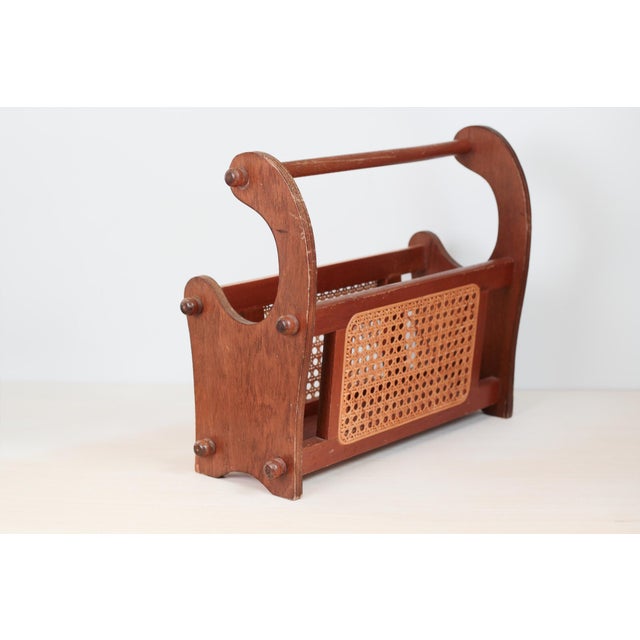 This vintage wooden magazine rack features woven cane panels, rounded peg accents, and a sculptural silhouette. A...