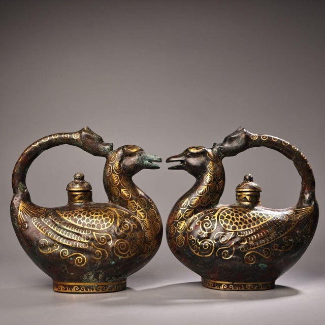 This striking pair of antique bronze vessels, or ewers, is finely modeled in the form of phoenixes, traditional symbols of...