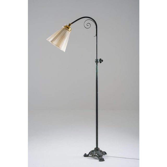 Graceful Swedish floor lamp from the 1940s, crafted in patinated brass. The lamp features a slender adjustable stem with...
