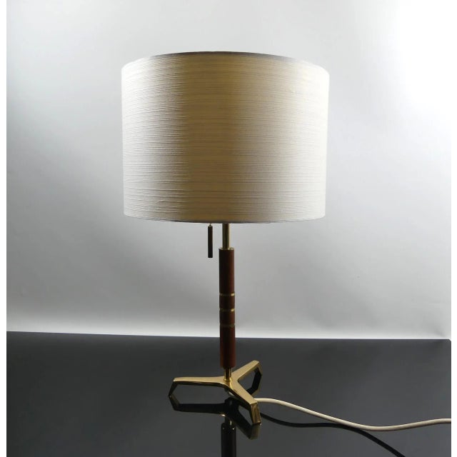 Decorative mid century table lamp with a tripod base made of teak and brass. I have official proof of authenticity such as...