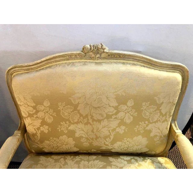 A pair of Louis XV style lounge chairs by Maison Jansen in their original fabric. A finely carved pair of chairs having a...