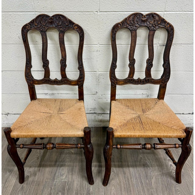 This is a charming pair of antique French Provincial side chairs featuring beautifully carved crest rails with shell and...