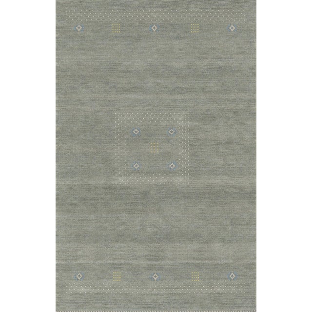 A hand-knotted wool rug, made in India and measuring 4' x 6'. An open, largely solid field with restrained detail at the...