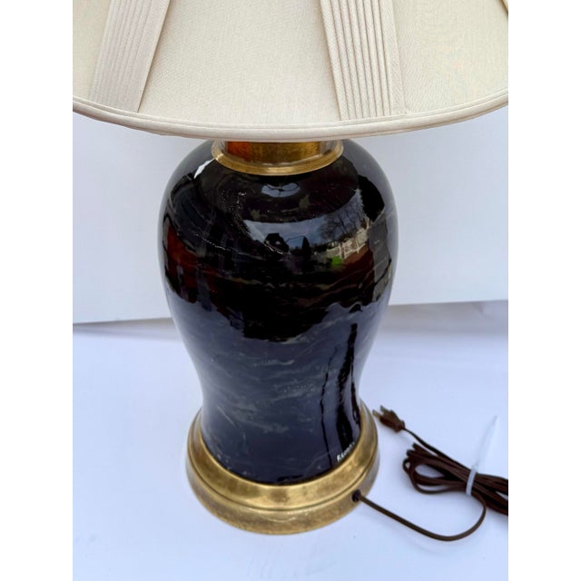 A striking signed Frederick Cooper table lamp featuring a glossy black marbleized body with warm gold veining, paired with...