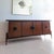 Rare sculptural mid century walnut sideboard by Helen Hobey Baker, USA 1960s. Brutalist metal medallions on the doors....