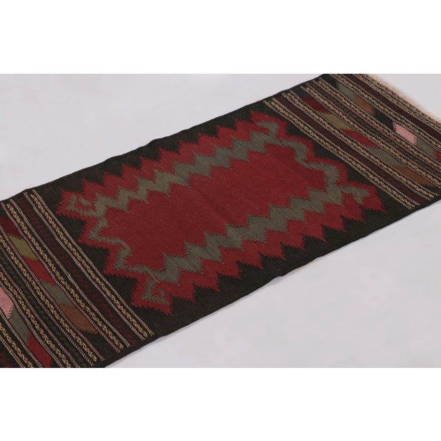 Hand-knotted in wool circa 1950-1960, this 2x5 vintage Persian flatweave runner Kilim is a particularly nuanced and...