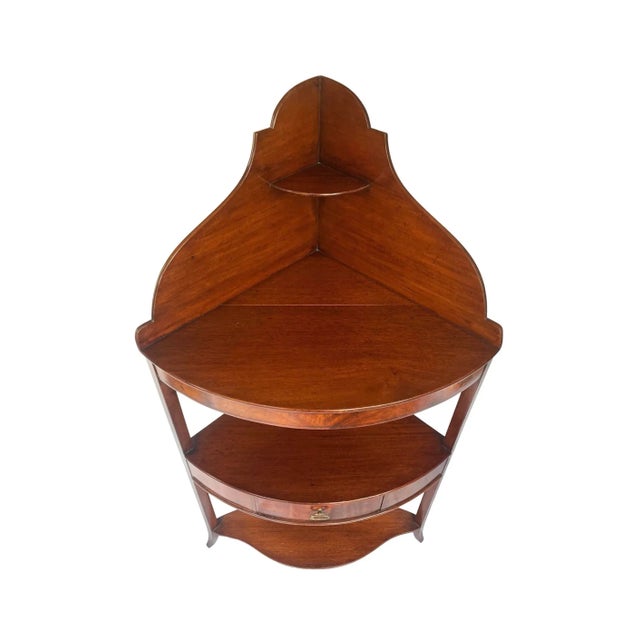 A very fine George III three-tier corner washstand of mahogany inlaid with ebony. Stunning bookmatched flame mahogany...