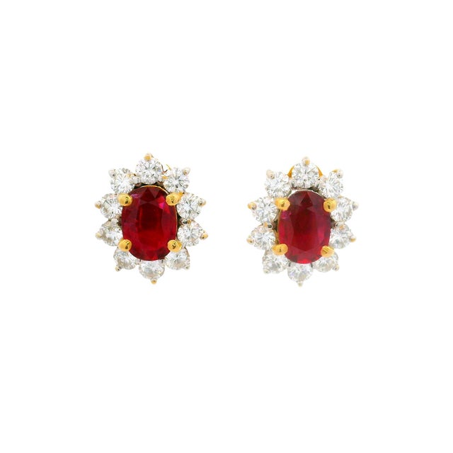 Crafted in 18k yellow gold, these earrings feature a captivating design. At the center, vibrant red rubies are surrounded...