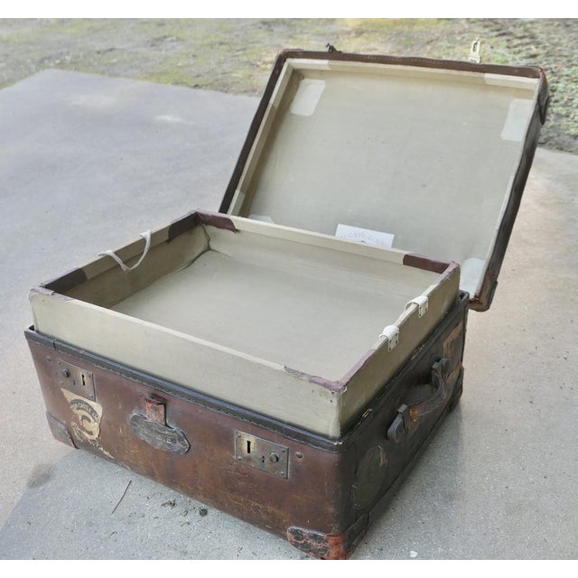 A leather bound “osilite” trunk suit case by h j cave & sons the trunk is dark bound in leather, it has reinforced corners...