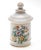 Pretty little apothacary vessel with floral decoration on the front. The vessell has gold bands. The lid has a round dot...