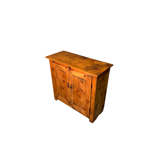 A small two-door sideboard made of fir wood, dating back to the early 1900s. Simple and functional in design, it features...