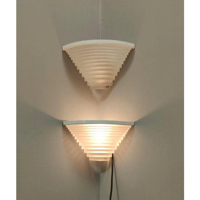 Made in Italy, 1980s. This is a pair of Italian vintage wall lights with white sanded glass shade on a varnished metal...