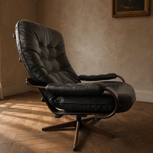 A vintage Scandinavian-style lounge chair from the 1970s, featuring black tufted leather upholstery and an elegant...