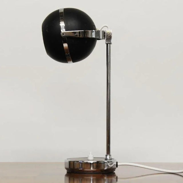 A 1960s black and silver desk lamp with movable head . This piece is attributed to the mentioned designer/maker. It has no...