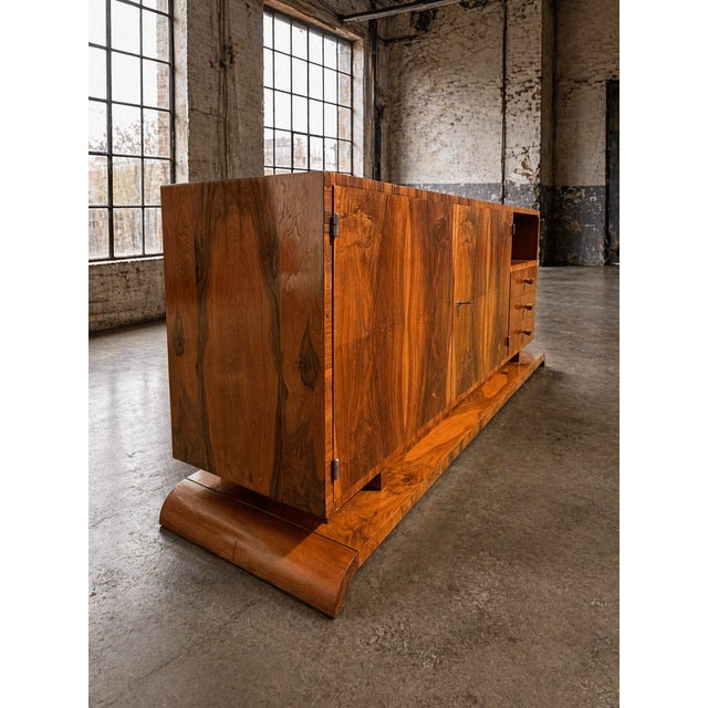 A striking Art Deco sideboard crafted in richly figured walnut veneer, showcasing a bold symmetrical grain pattern and...