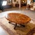 An elegant oval coffee table featuring a richly figured burl veneer top with fine inlaid marquetry: floral motifs at the...