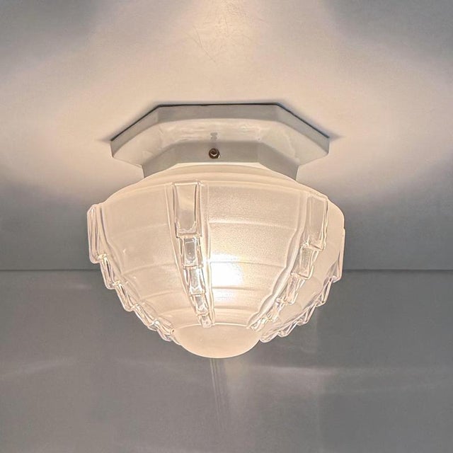Art deco ceiling light in white glazed porcelain with a globe of partially matte sandblasted glass featuring stepped...