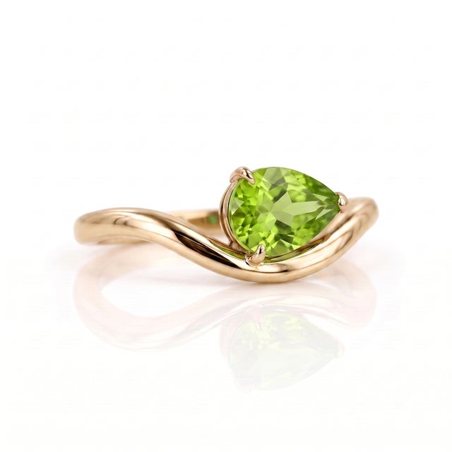 Capture the essence of spring with this brilliant, pear-cut Peridot ring. The striking lime-green gemstone, measuring...