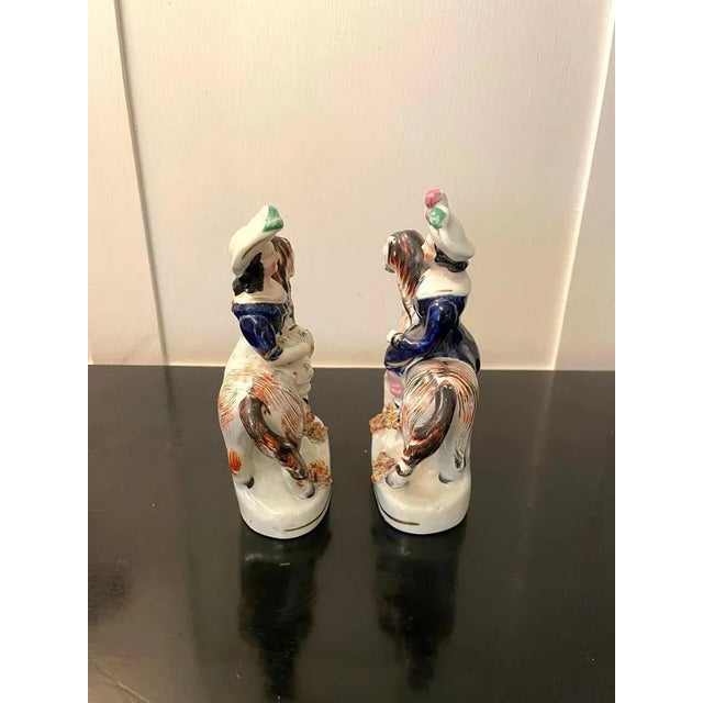 Pair of antique Victorian Staffordshire figures of two ladies in period clothing riding colourful horse’s on oval shaped...