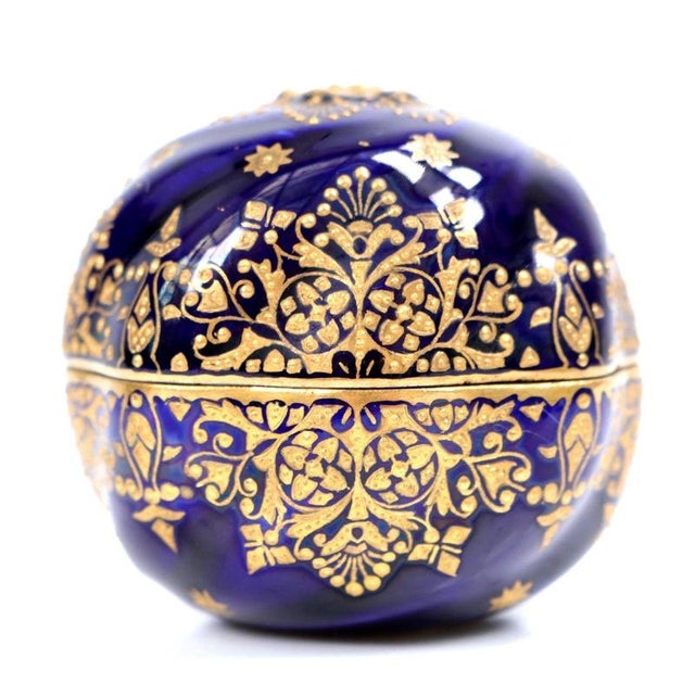 Swirling spiral fluting and deep cobalt blue glaze define this spherical porcelain trinket box, decorated throughout with...
