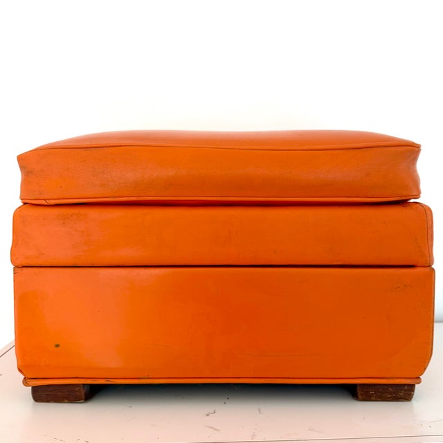 Authentic vintage 1960s orange Naugahyde (vinyl) storage ottoman. Rectangular. Wood feet. The top lifts off to reveal the...