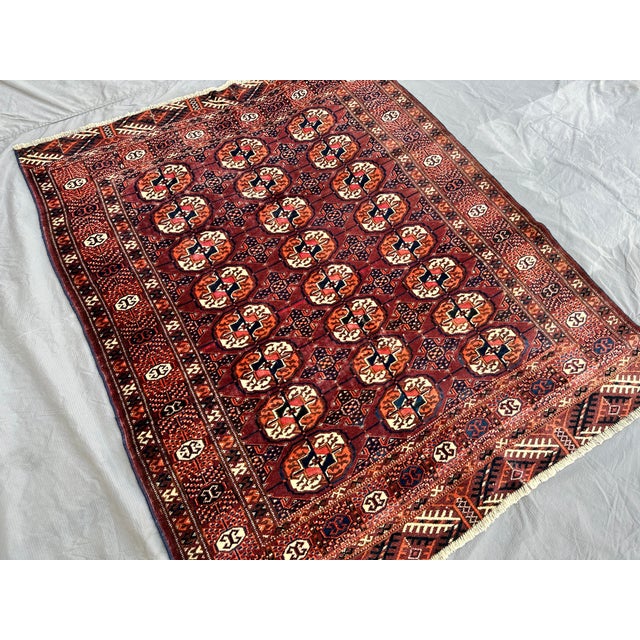 This hand-knotted Bokhara rug features three tidy columns of octagonal "elephant's foot" guls in rust and ivory, set...