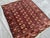 This hand-knotted Bokhara rug features three tidy columns of octagonal "elephant's foot" guls in rust and ivory, set...