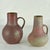Two hand turned studio pottery tall vases with ears with in earth tone glazes form deep dark red to grey-green. They are...