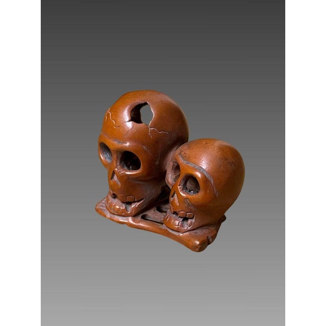 Netsuke at momento mori, Japan, Meiji era, 19th century. Depicts two skulls resting on bones. Signed under the base....