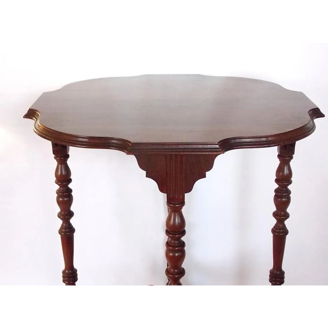 Walnut side table featuring four turned legs and cross bars at bottom with central finial. No maker's mark.