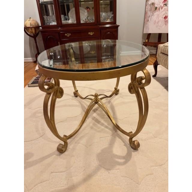 Beautiful, traditional-style oval coffee table featuring a thick, beveled glass top and an ornate gold-tone metal base....