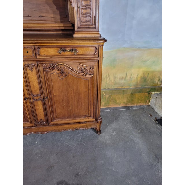 An elegant two-part louis xv style buffet crafted from walnut, featuring richly carved rococo-inspired decoration. the...