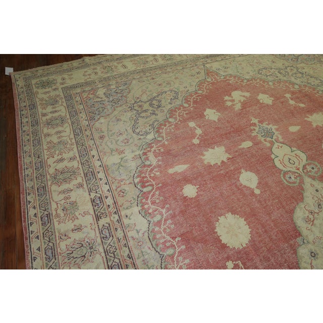 An oversize old Turkish Oushak rug, with ivory, soft brown, and light green accents and predominantly soft red tone, circa...