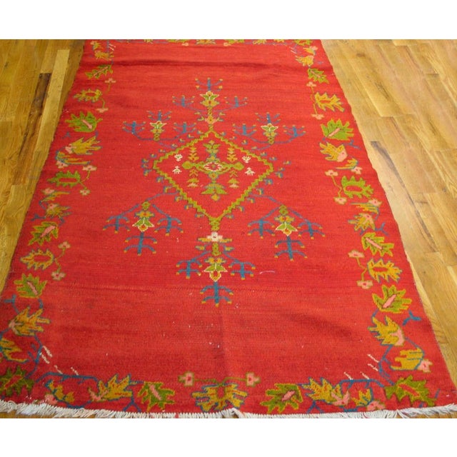 The saturated red open field bleeds over into an outlined border of yellow and green leaves. An open stepped lozenge...