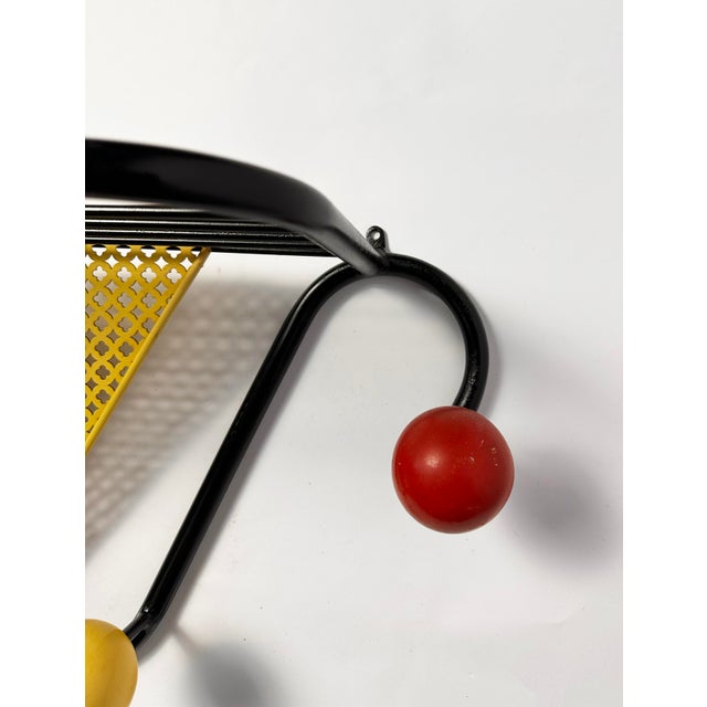 A party hat for your hallway. Sinuous black tubular frame, inverted triangle of yellow lacquered perforated steel, a...