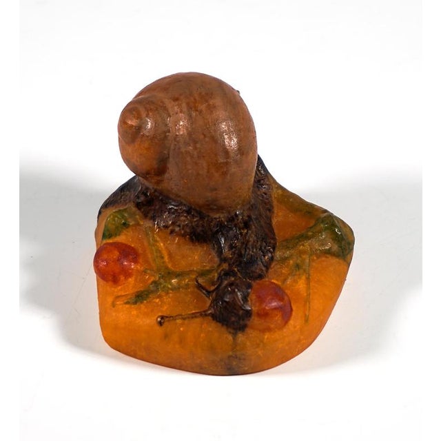 Pâte de verre presse-papiers 'escargot': a dark brown snail with a light brown shell, crawling over scattered green twigs...