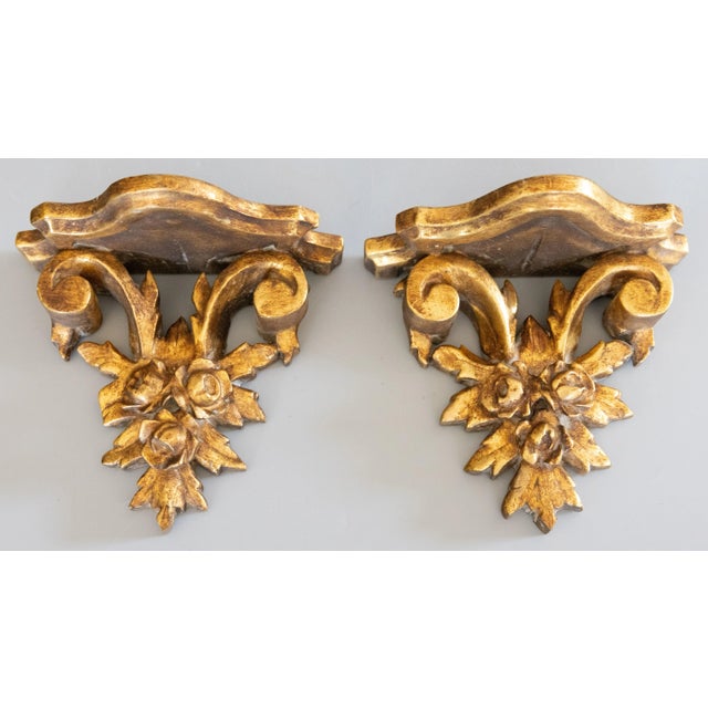 A lovely pair of vintage Italian gilded wood and gesso wall brackets shelves, circa 1950. They are decorated with lovely...