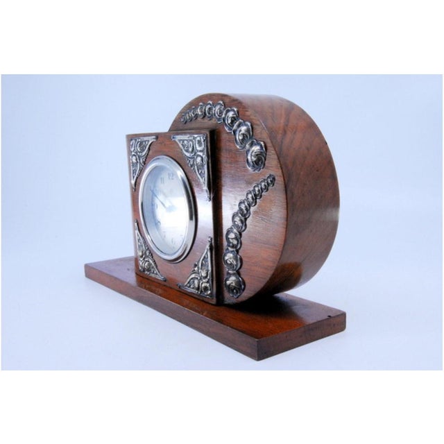 Art Deco Wooden Table Clock with Silver Applications, in Very Good conditions. Designed 1890 to 1919 This piece has an...