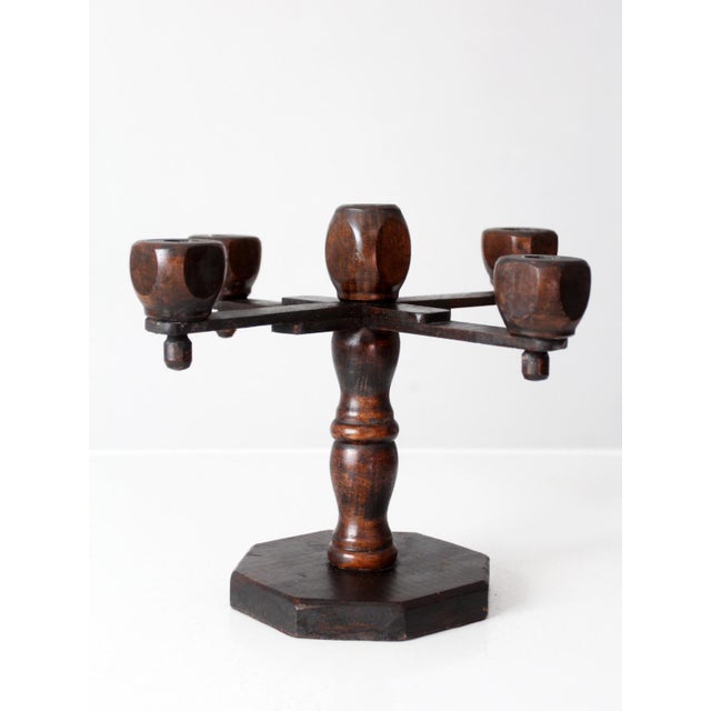 A vintage five-arm wood candelabra with a sculptural Spanish Revival silhouette. Five turned candle cups rise from crossed...