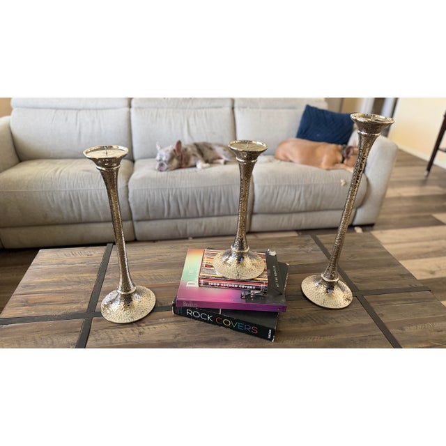 This sophisticated graduated set of three authentic Arteriors Home hammered nickel candlesticks showcases the brand’s...