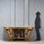 Carved and gilded wooden console table. The tripartite band beneath the top features floral carvings and masks, supported...