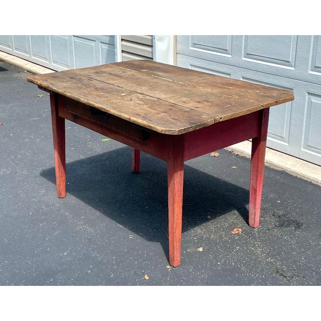 This exceptional 19th-century primitive farmhouse table features a beautifully weathered, scrubbed pine plank top paired...